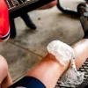 Мужчина-велосипедист в велоформе и обуви поднимает колено с пакетом льда.