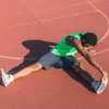 Мужчина растягивает свои подколенные сухожилия на улице
