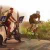 Триатлеты тренируются для триатлона на стационарном велосипеде Peloton. Триатлеты тренируются для триатлона на стационарном велосипеде Peloton.
