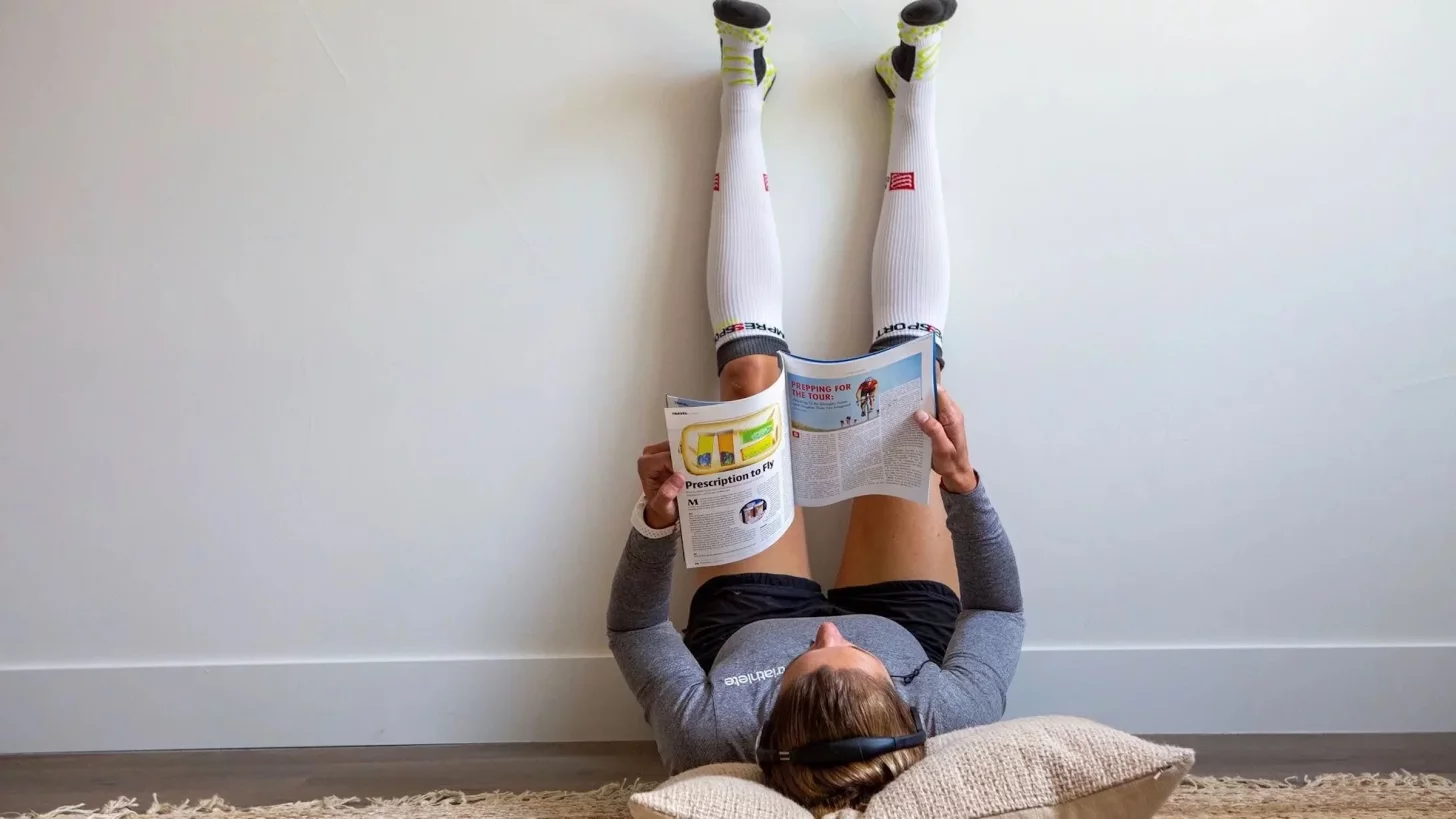 Спортсмен отдыхает и восстанавливается, читая журнал, положив ноги на стену