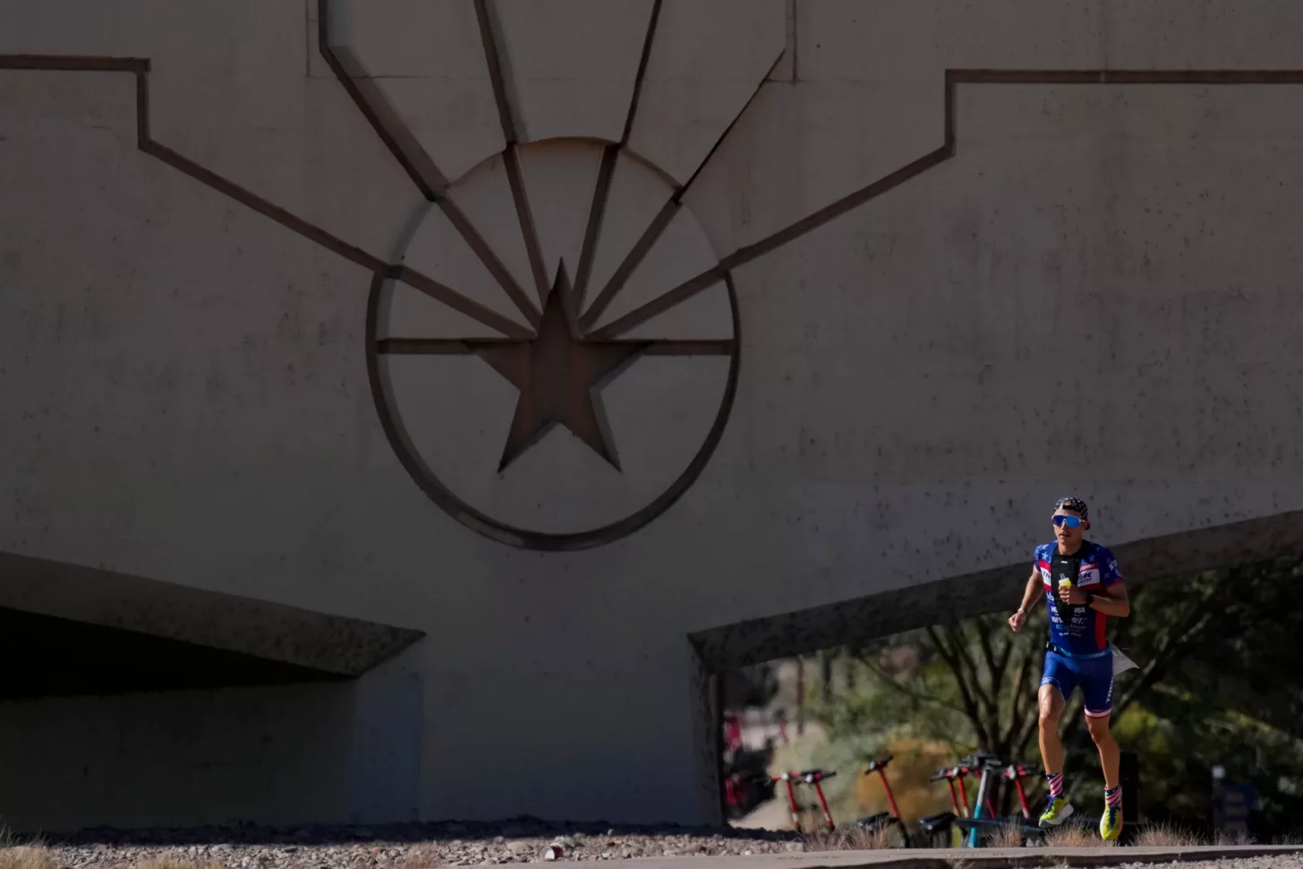 Трехцикловая, точка-точка беговая трасса на Ironman Arizona ведет спортсменов вдоль озера Темпе Таун и через парк Папаго. Трехцикловая, точка-точка беговая трасса на Ironman Arizona ведет спортсменов вдоль озера Темпе Таун и через парк Папаго.