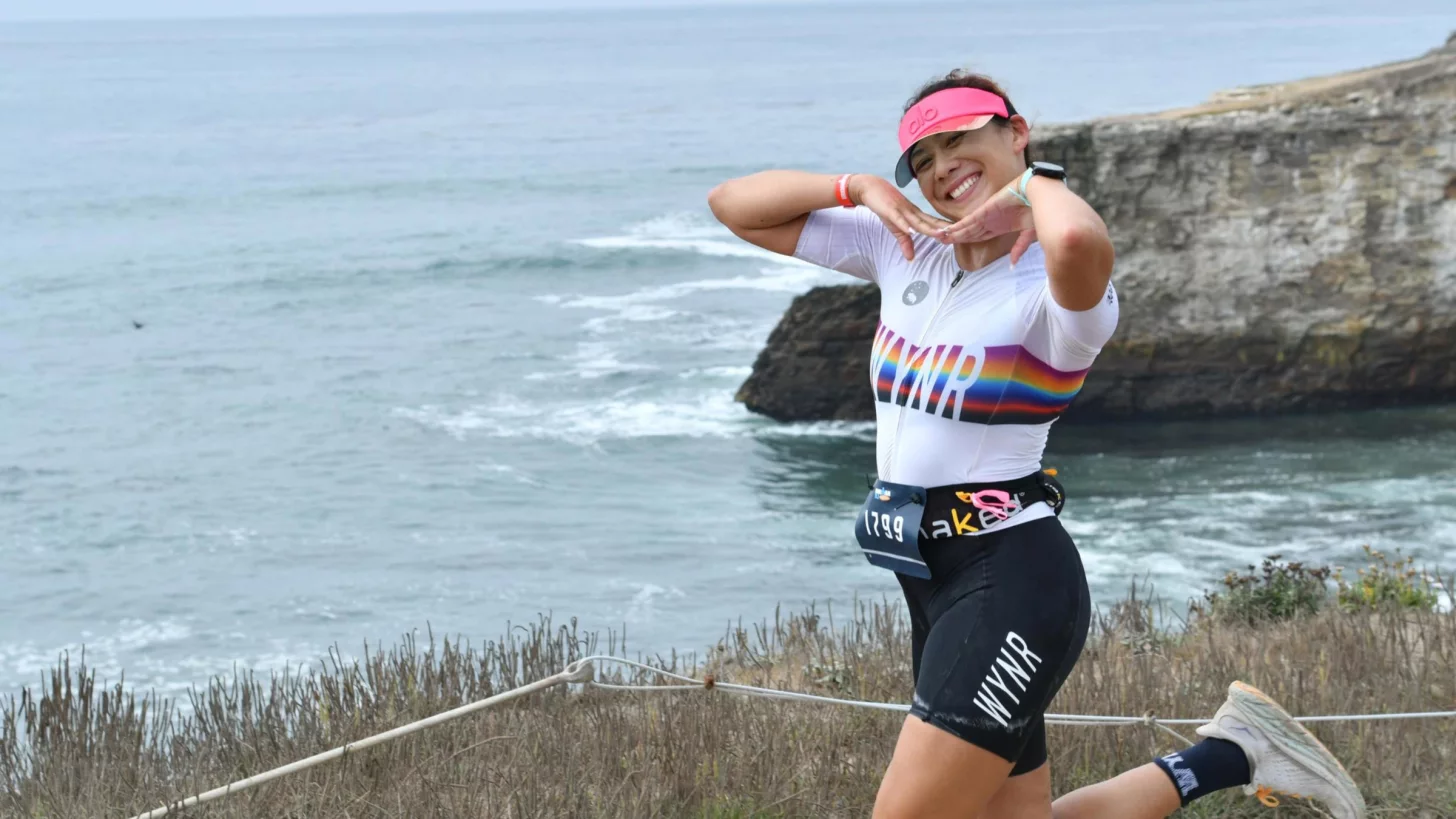 женщина-триатлет в возрастной категории в триатлонной экипировке бежит вдоль океана