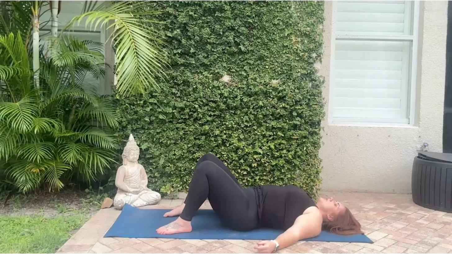 Женщина на коврике для йоги наклоняет таз.