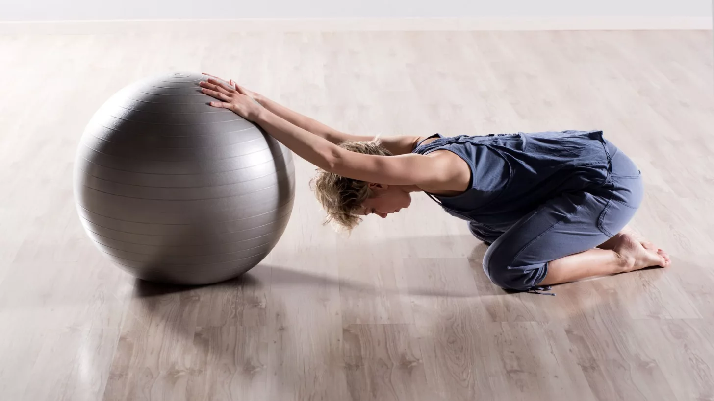 Женщина выполняет упражнения на растяжку для напряжённых плеч