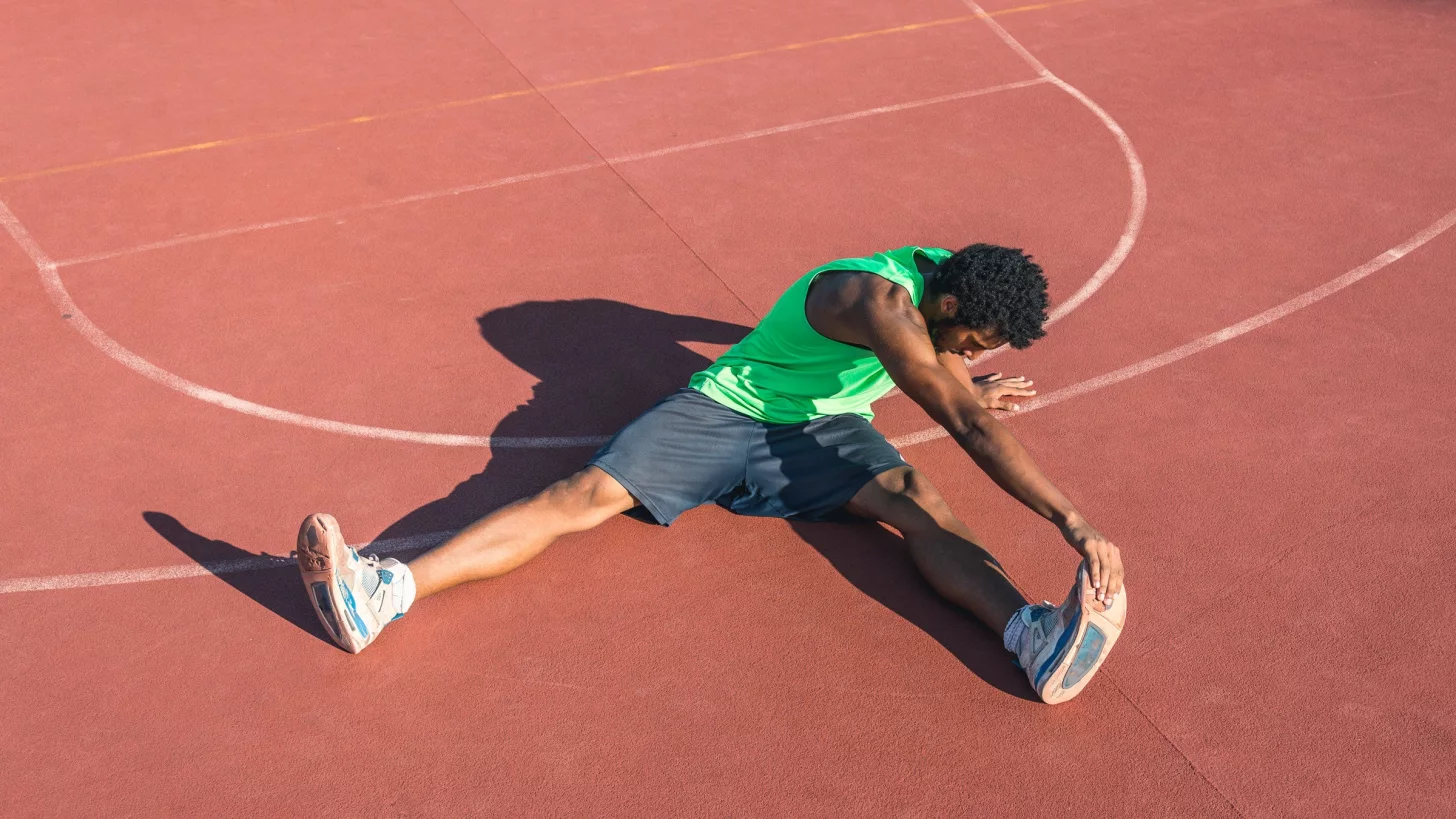 Мужчина растягивает свои подколенные сухожилия на улице