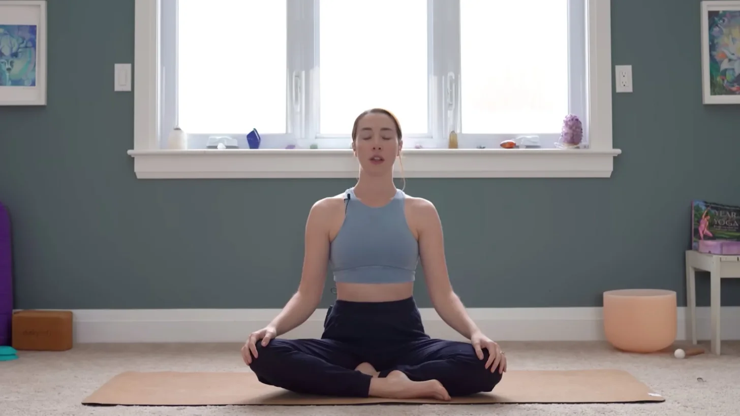 Yoga With Cassandra практикует сидение со скрещенными ногами во время медитации перед 15-минутной медленной практикой йоги.